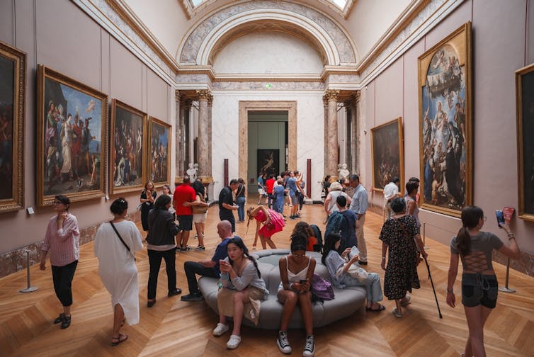 Visitantes en una sala con bastante gente dentro de un museo.