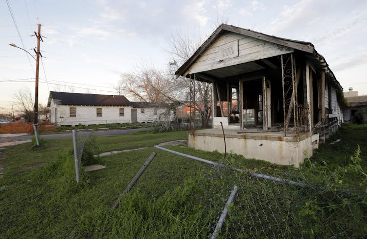A house missing it walls and with a torn-down fence.