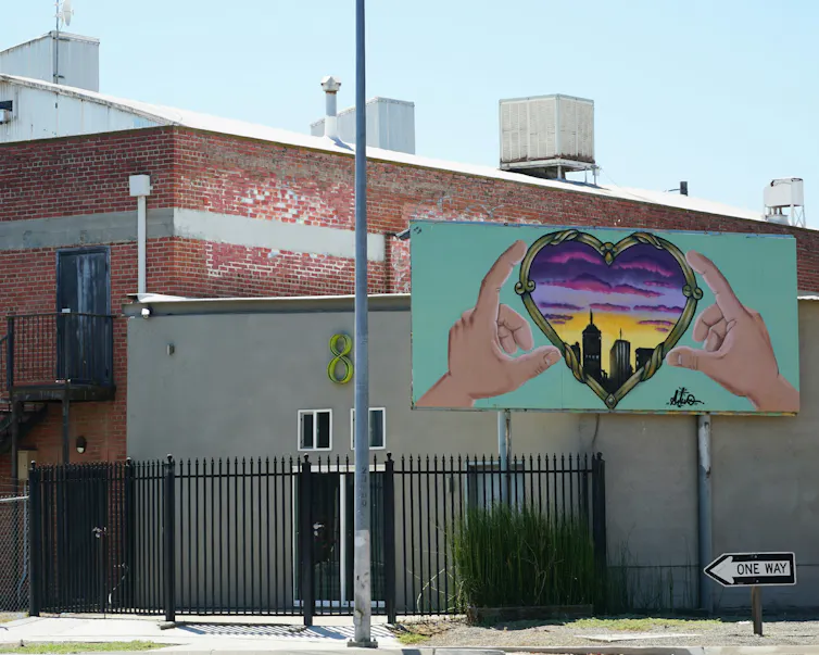 A grafitti mural of heart hands around a city.