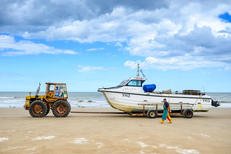 A small fishing boat is pulled in by a tractor