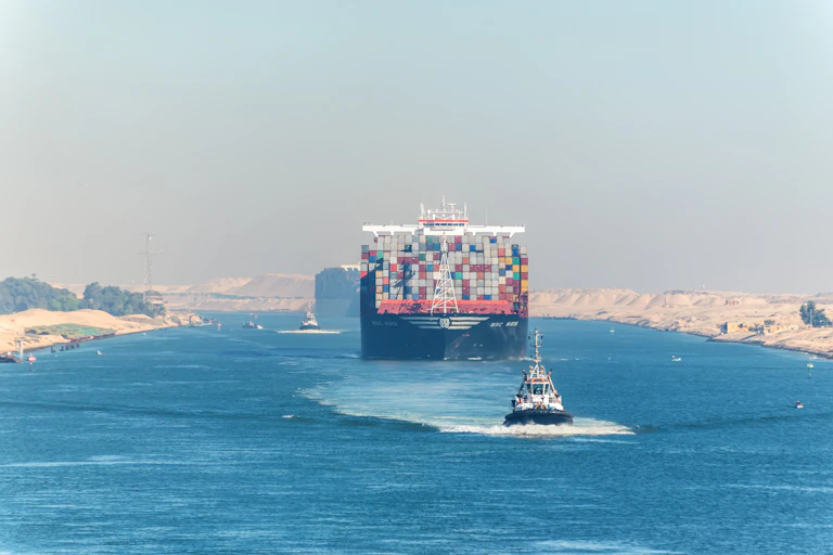 Dos cargueros navegando por el canal de Suez con otros dos barcos pequeños acompañándoles