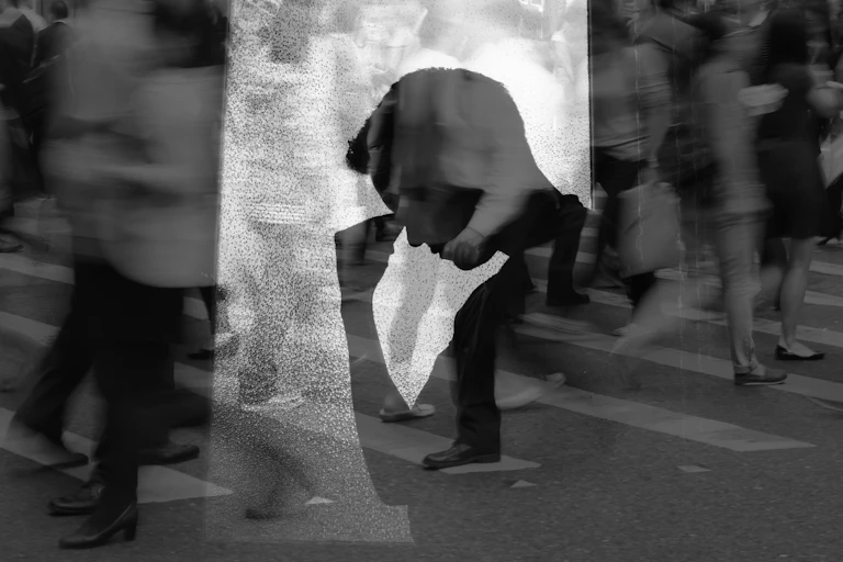 Silhouette of man looking anxious against blurred background of crowded street.