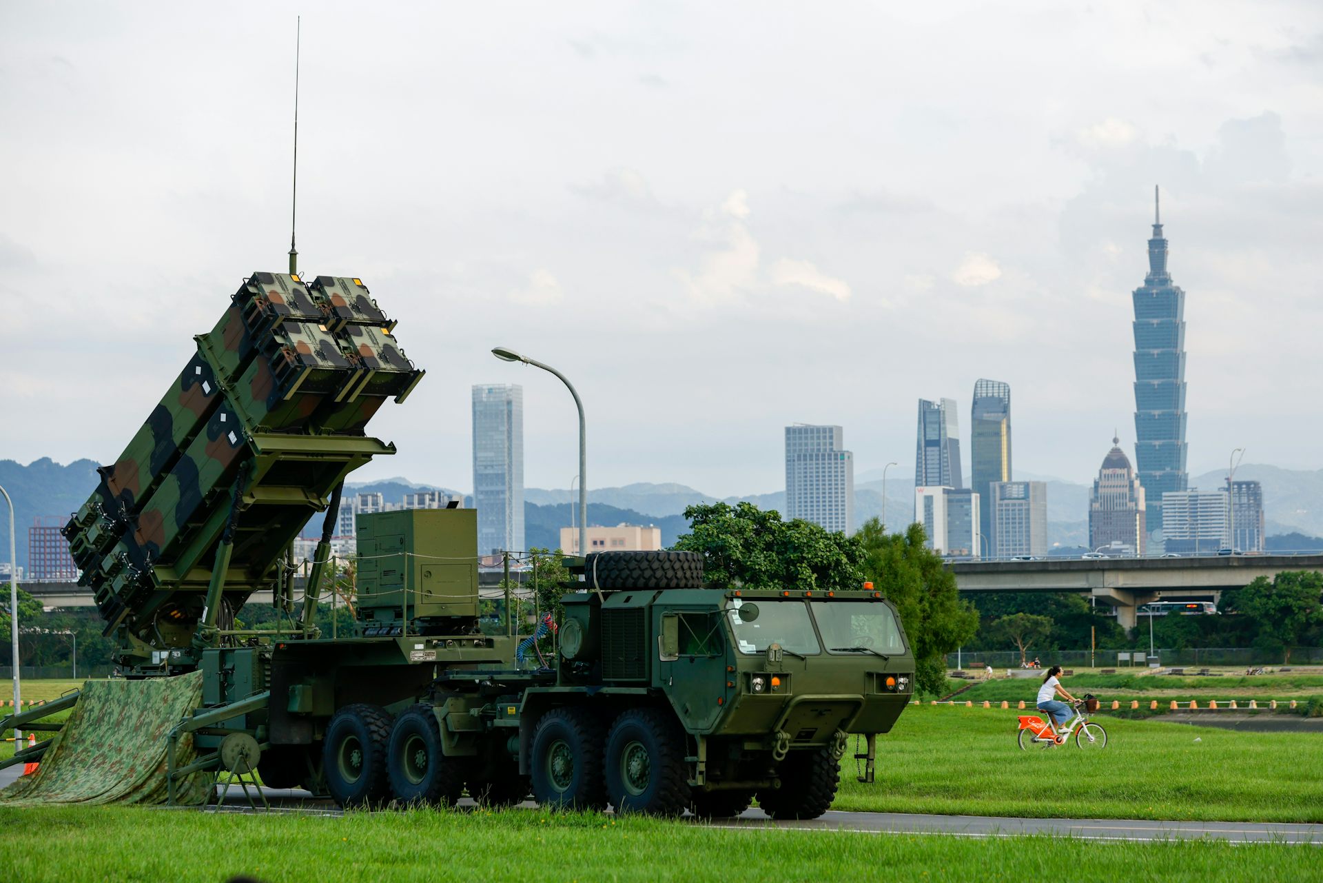 A person bikes past a Taiwanese air defence system in a park in Taipei.