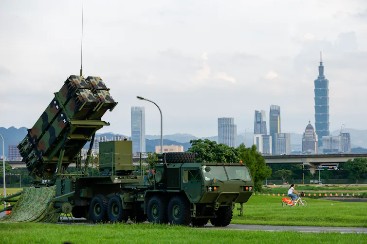 A person bikes past a Taiwanese air defence system in a park in Taipei.