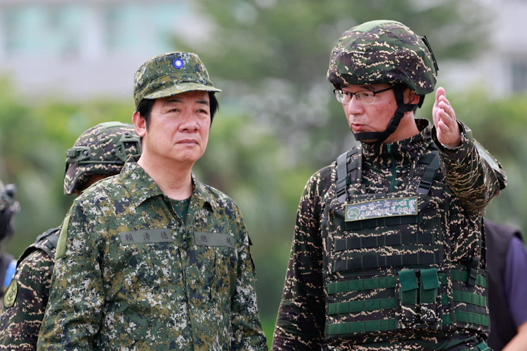Taiwanese president, William Lai Ching-te, dressed in military clothing as he speaks to a military officer.