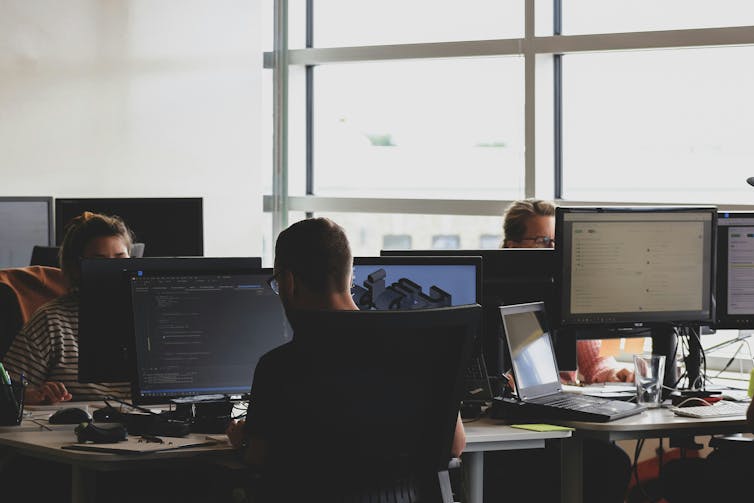 People in an office sit at desks working on computers