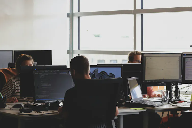 People in an office sit at desks working on computers