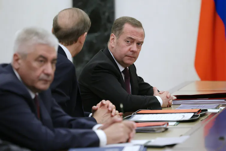 Russian president and Putin ally, Dmitry Medvedev, sits at a table with two other senior Russian politicians.