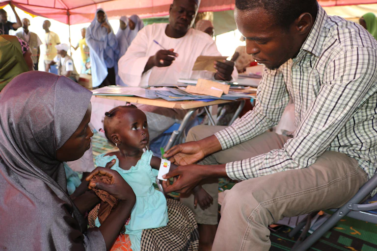 A man measures the arm circumference of a small child