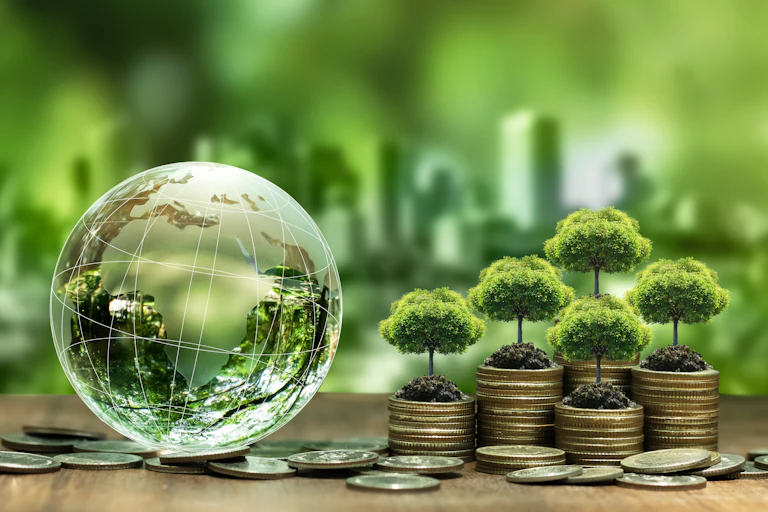 A glass globe featuring Africa next to a pile of coins with trees growing out of them, depicting climate finance