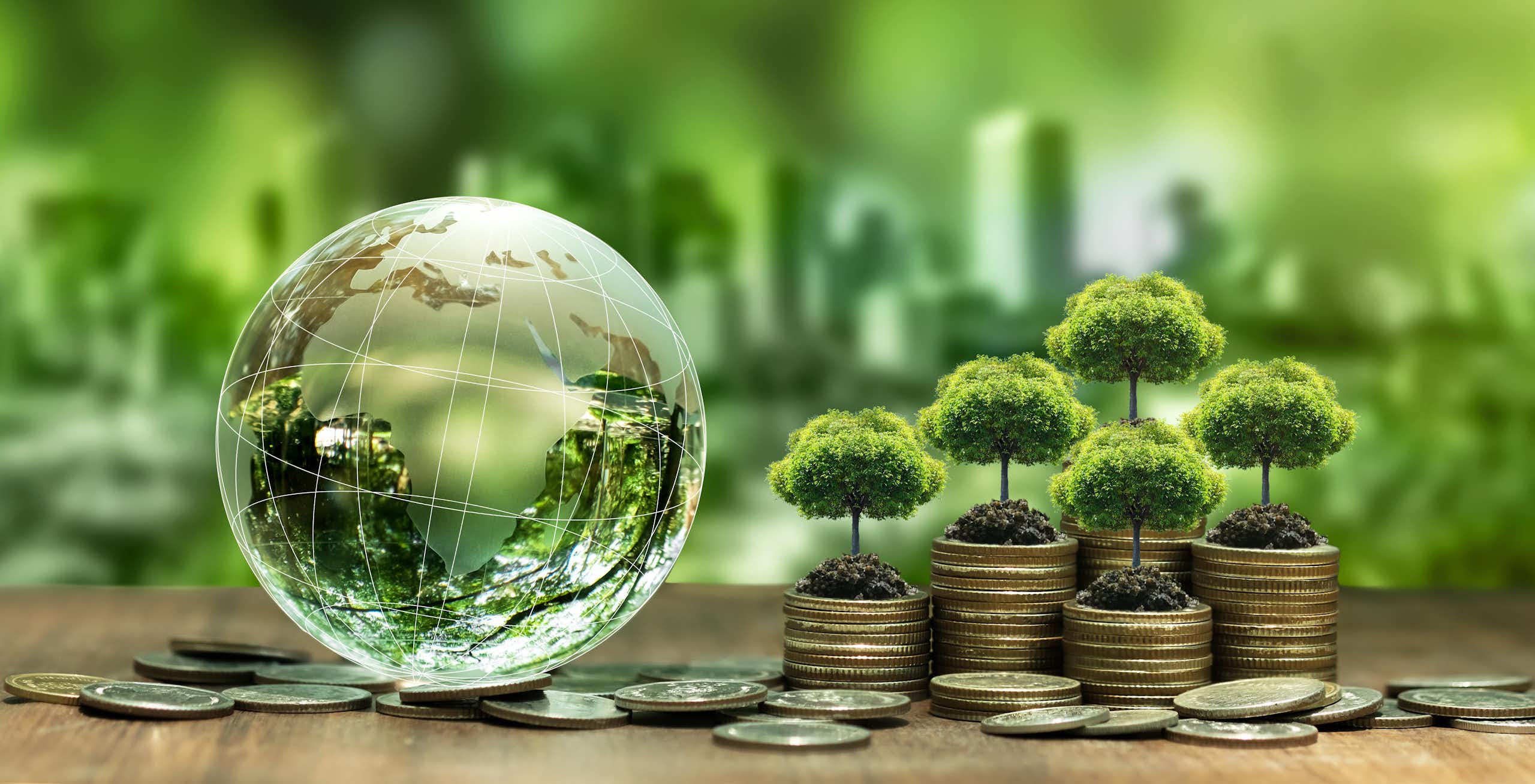 A glass globe featuring Africa next to a pile of coins with trees growing out of them, depicting climate finance