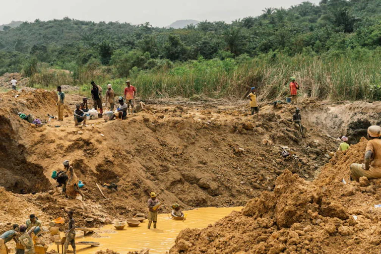 People at an excavated hole in the ground with water at the bottom