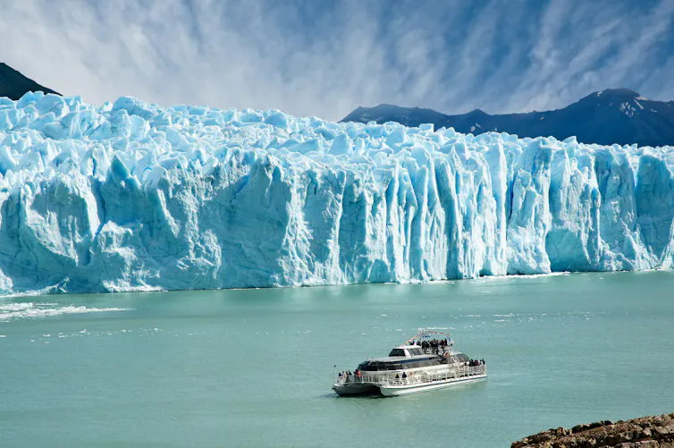 boat in front of large glacier front