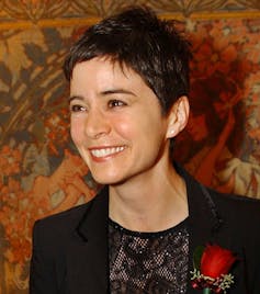 La mujer sonríe con rosa corsage.