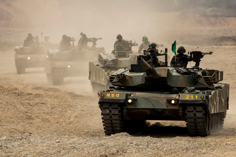 A column of tanks travelling through arid terrain.