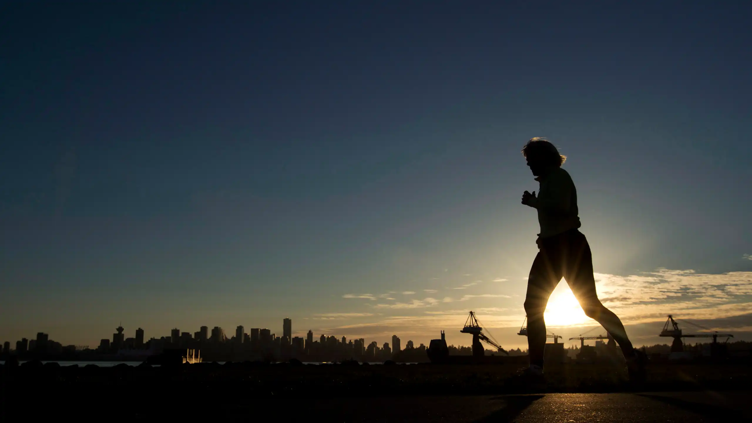 A woman is silhouetted as she runs along the water front in North Vancouver, B.C.