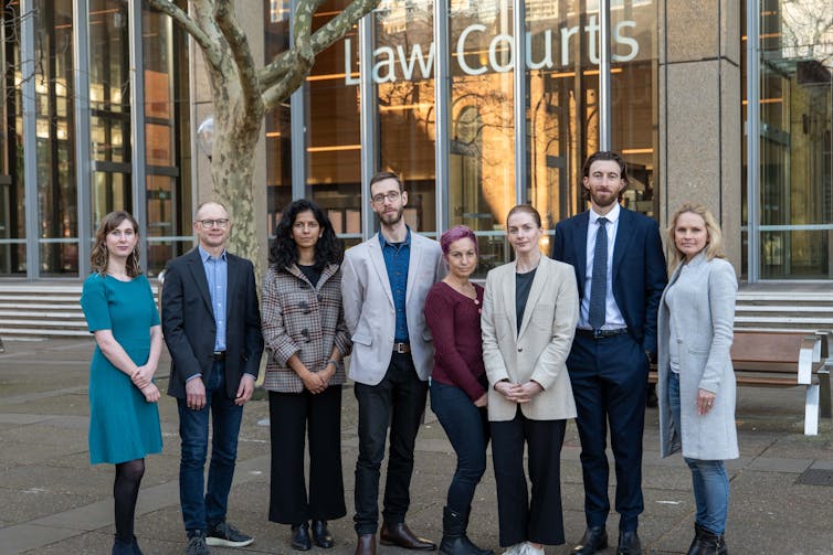 Eight people standing outside a courthouse