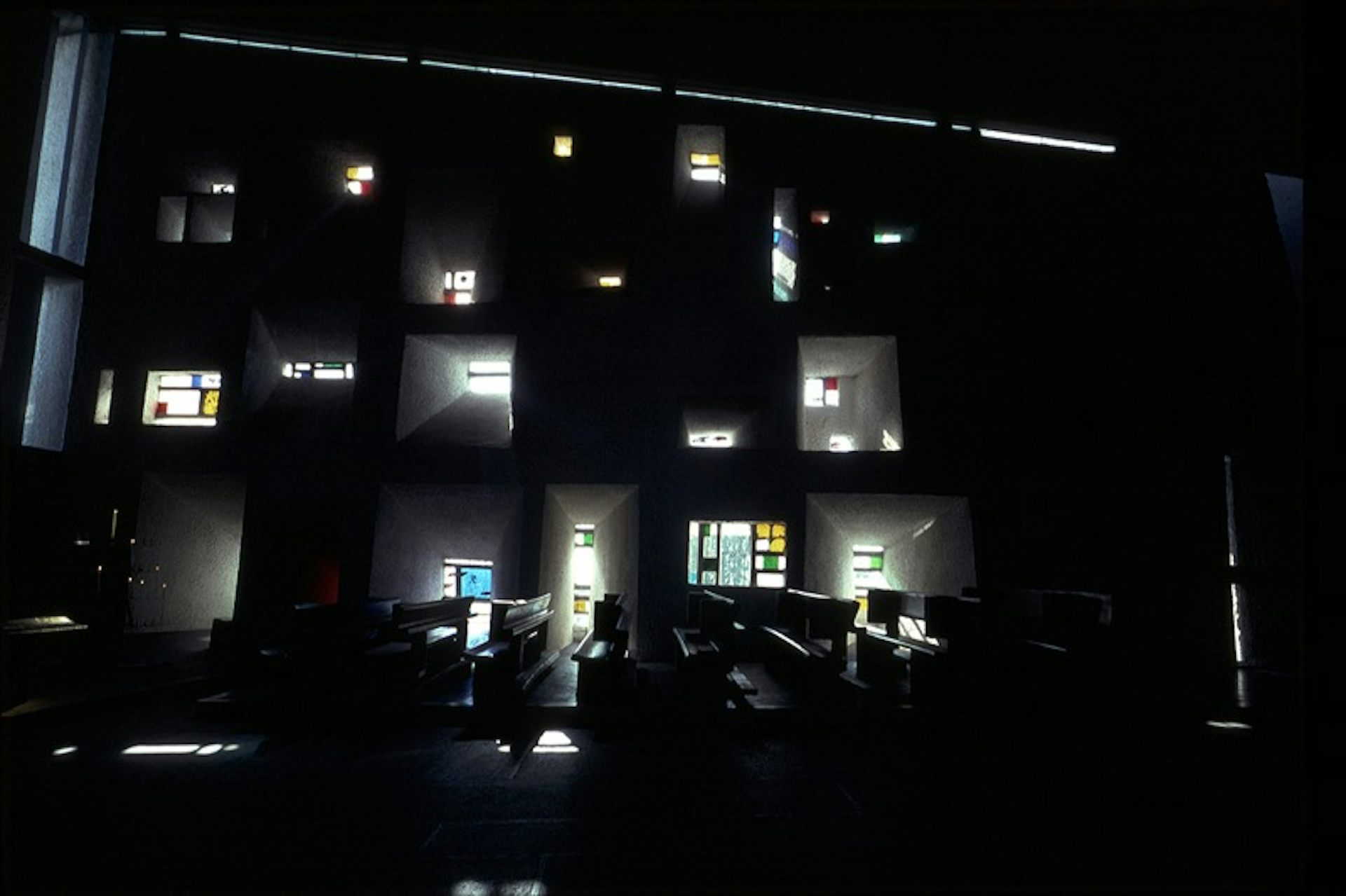 The interior of the chapel, in the darkness, while the light windows are filtered.