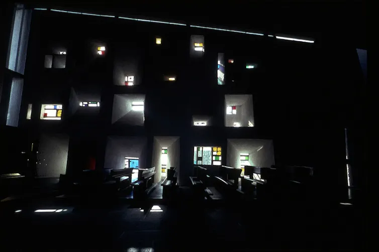 Interior de una capilla, en oscuridad, mientras la luz se filtra por los ventanucos.