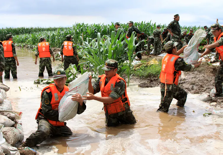 Chinese soldiers stacking sandbags in a flooded area.