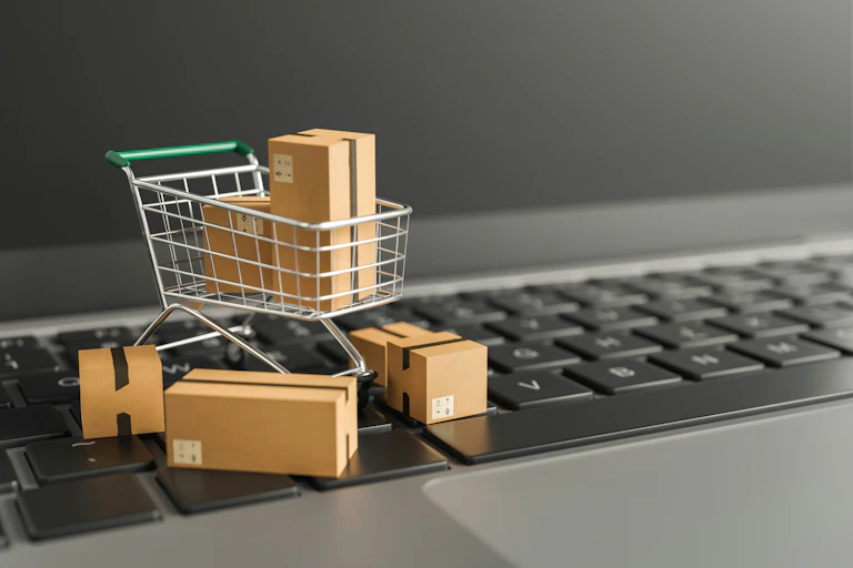 a miniature shopping cart and packages posed on a computer keyboard