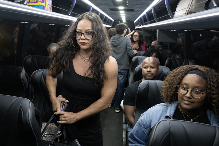 People on a bus, some standing and some sitting.