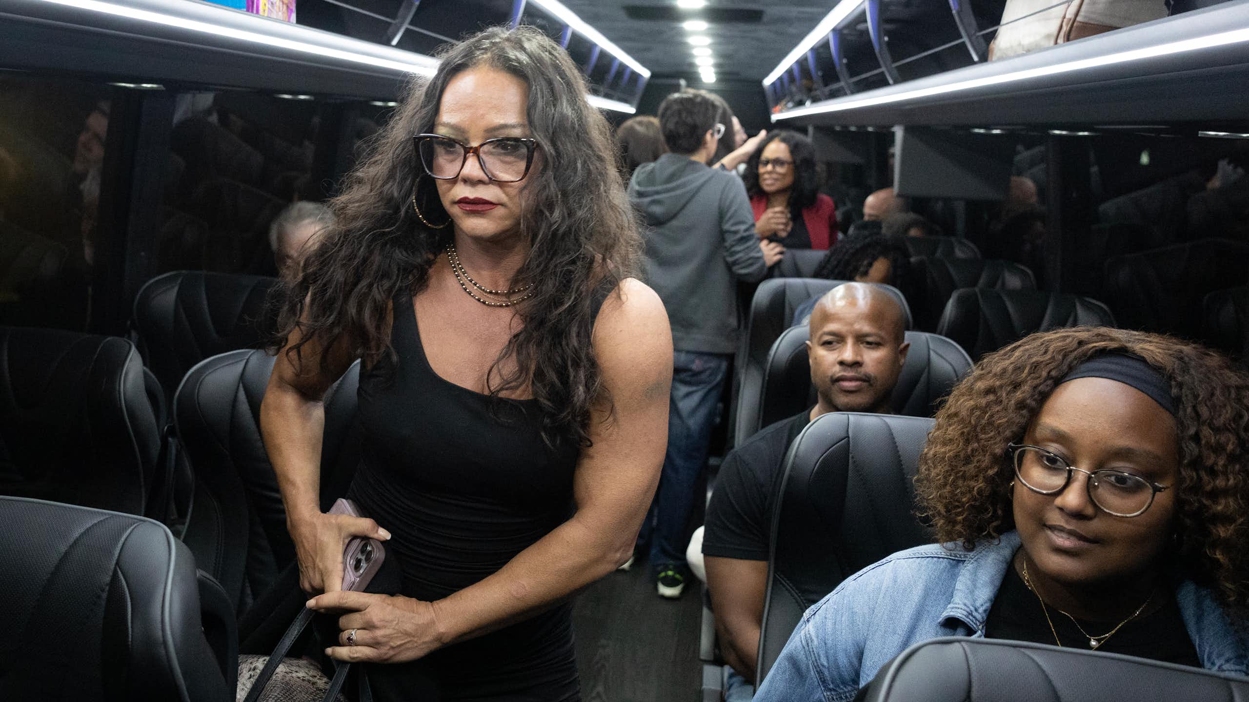 People on a bus, some standing and some sitting.