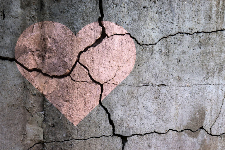 A broken heart drawing on a cracked wall.