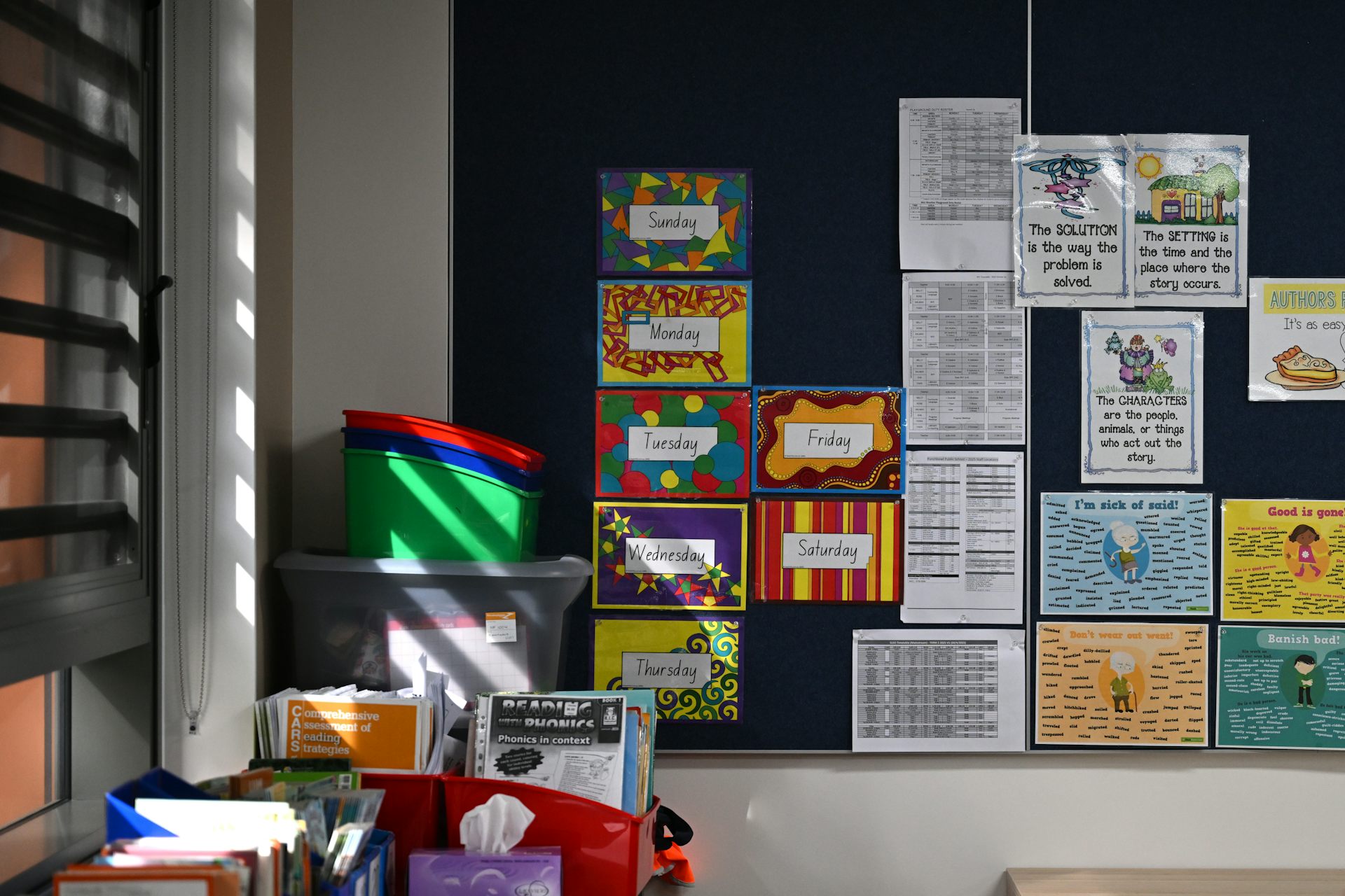 Books and resources on a wall and in containers in a school classroom.