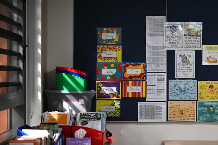 Books and resources on a wall and in containers in a school classroom.