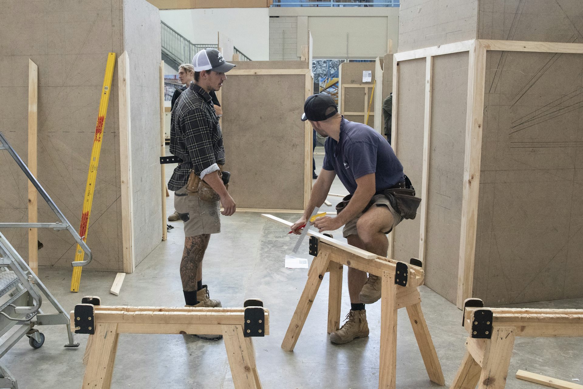 Two men work with timber in a TAFE training area.