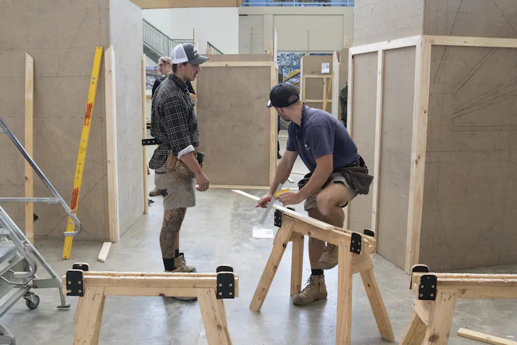 Two men work with timber in a TAFE training area.