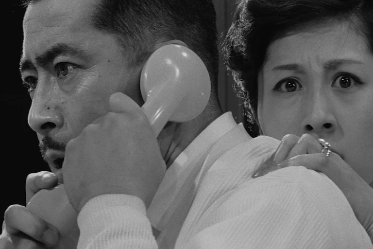 Three shocked Japanese people, one on a phone.