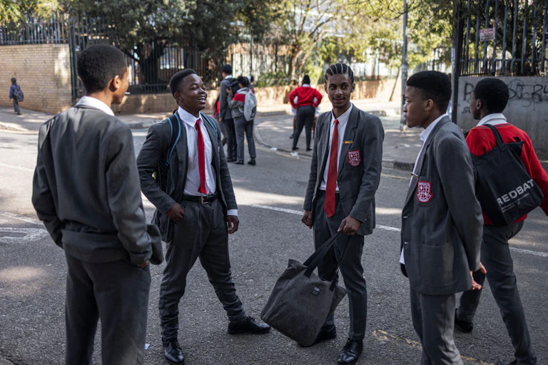 Boys in school uniform stand in a group. talking to each other