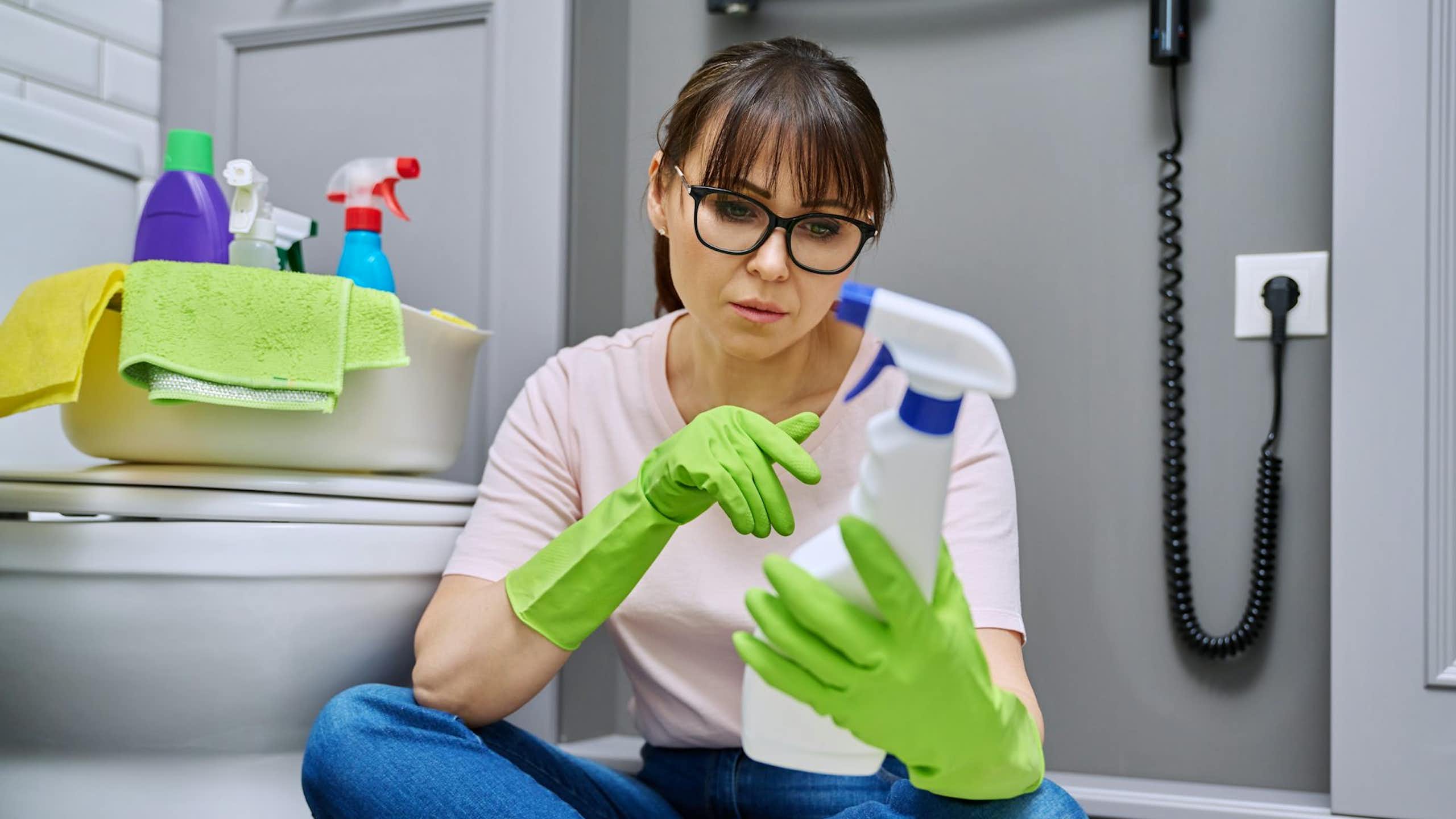 A woman appears to look at the label of a household product.