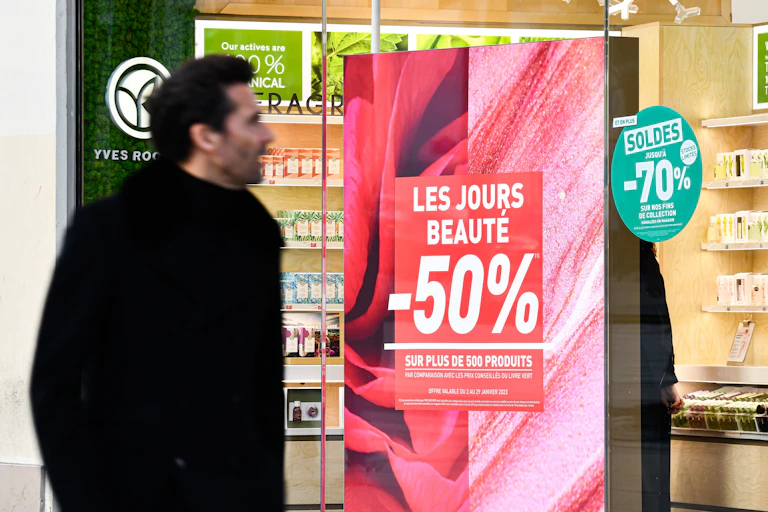 homme devant une vitrine affichant des promotions