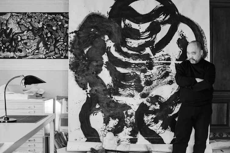 Pan next to one of his paintings