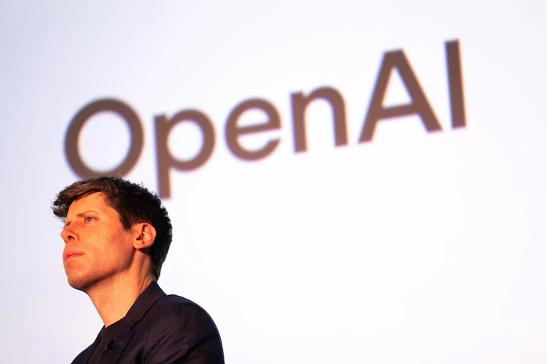 Sam Altman in front of an OpenAI sign