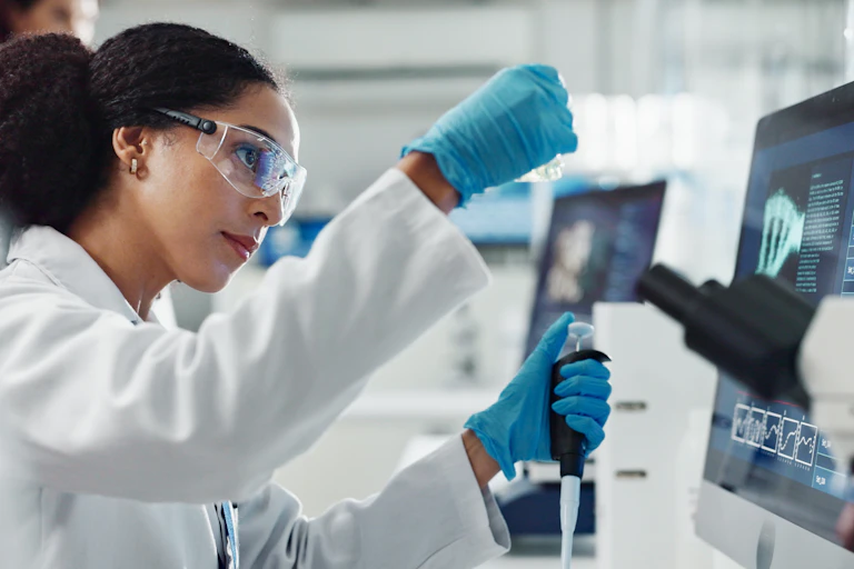 Une femme scientifique fait des manipulations dans un laboratoire, la pipette à la main.