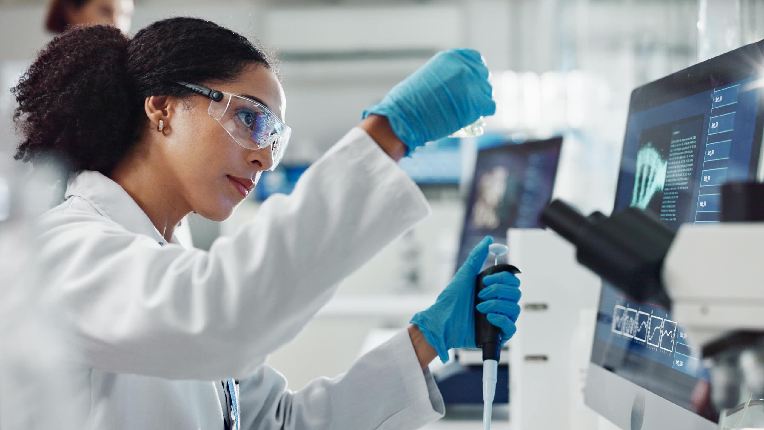 Une femme scientifique fait des manipulations dans un laboratoire, la pipette à la main.