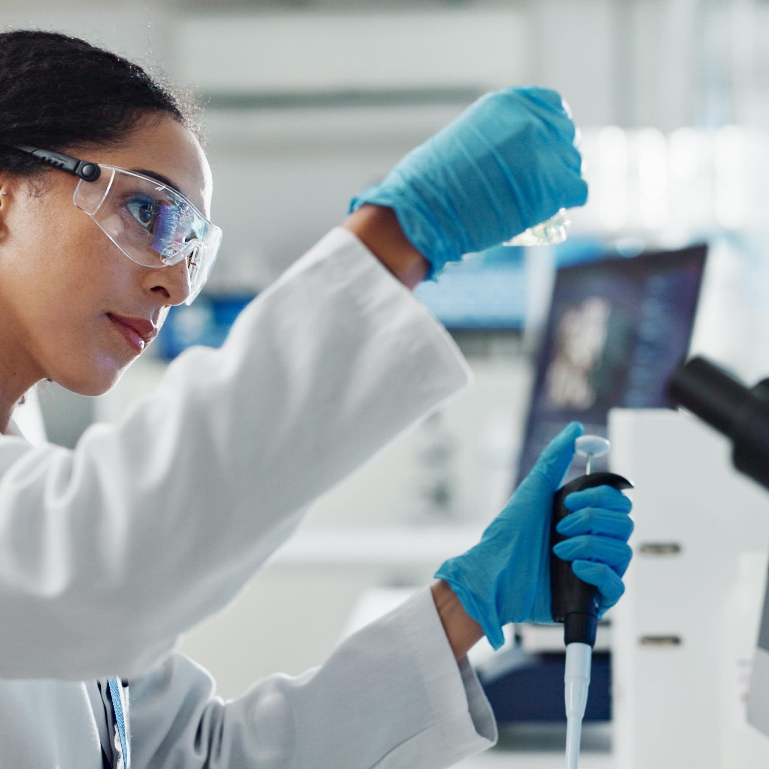 Une femme scientifique fait des manipulations dans un laboratoire, la pipette à la main.