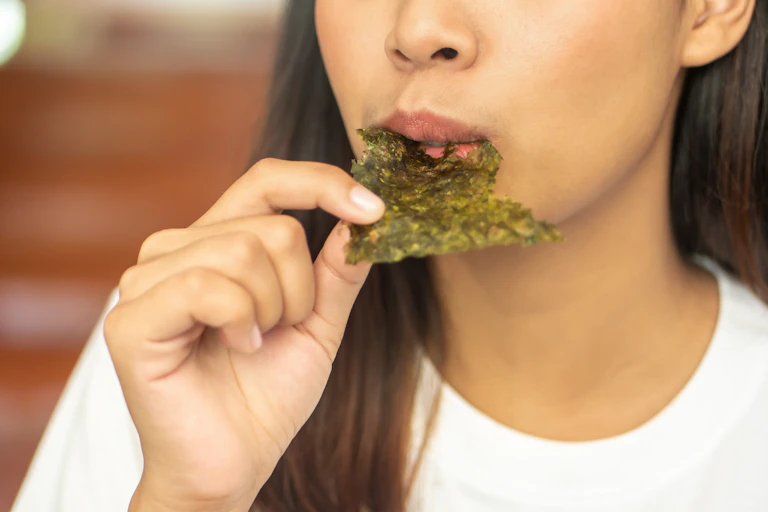asian woman eats dry seaweed