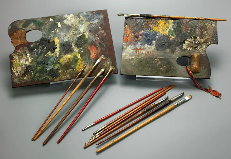 two boards with various colors of paint dried on them along with multiple paint brushes