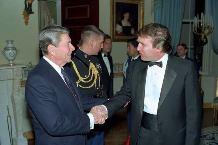 Reagan, standing in a reception line, shakes Trump's hand. Trump is wearing a tuxedo. Reagan a suit.