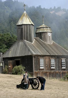 people look at a canyon in front of an old building that was part of a fort