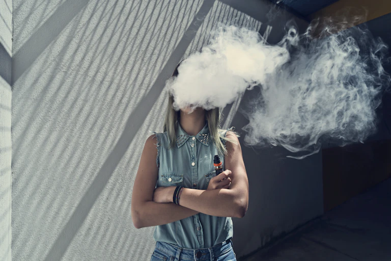 Young woman with her head in a cloud of vapor smoke
