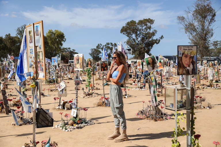 A woman stands amid memorials to the dead.