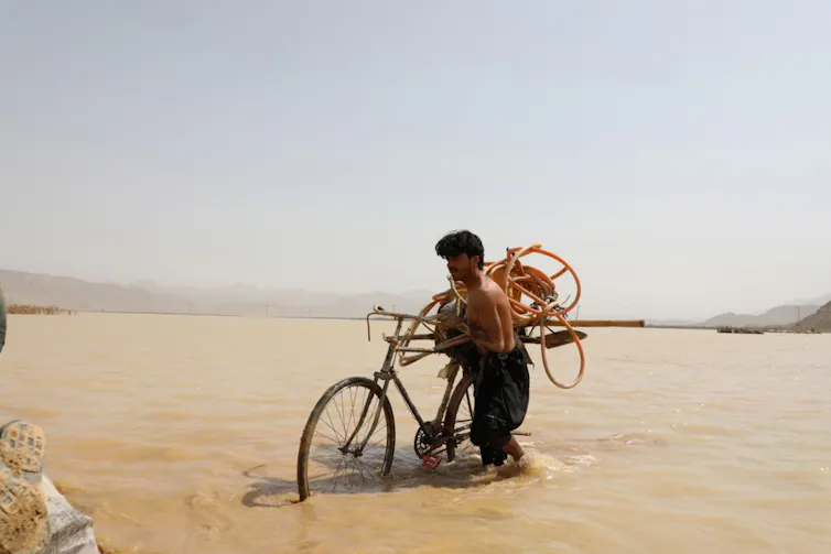 man pushes bike through floodwaters