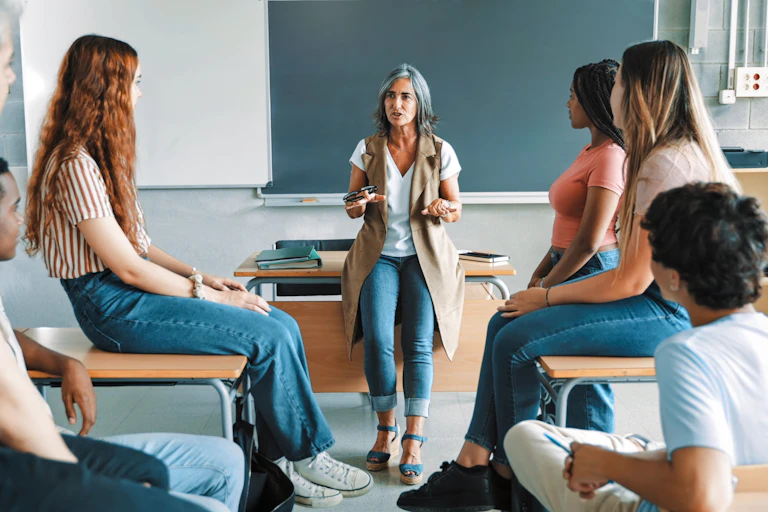 Una mujer dialoga con adolescentes sentados a los lados
