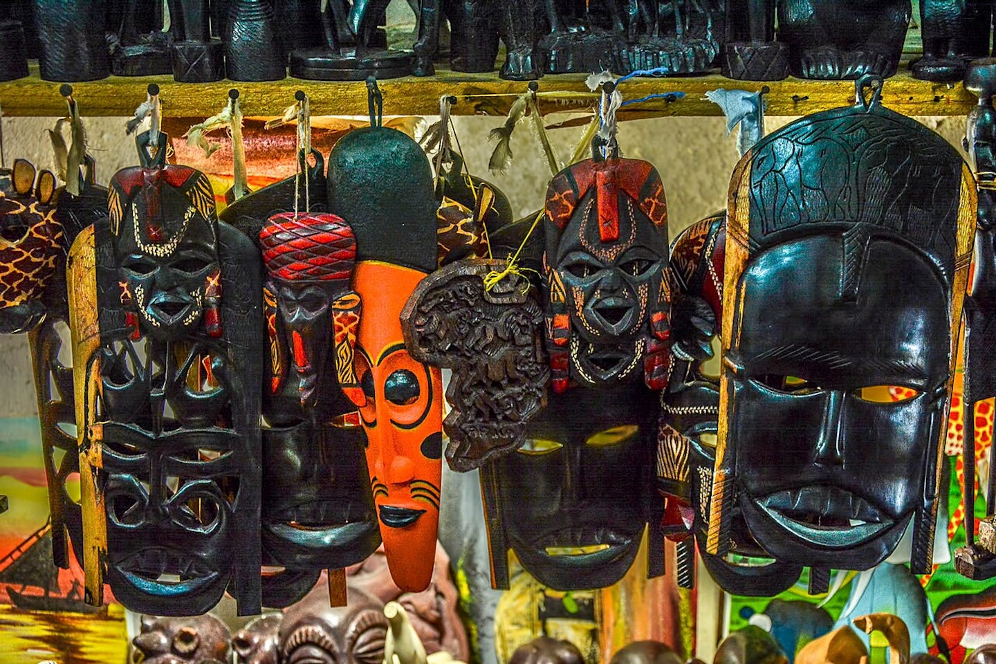A row of wood-carved African masks, all similar.